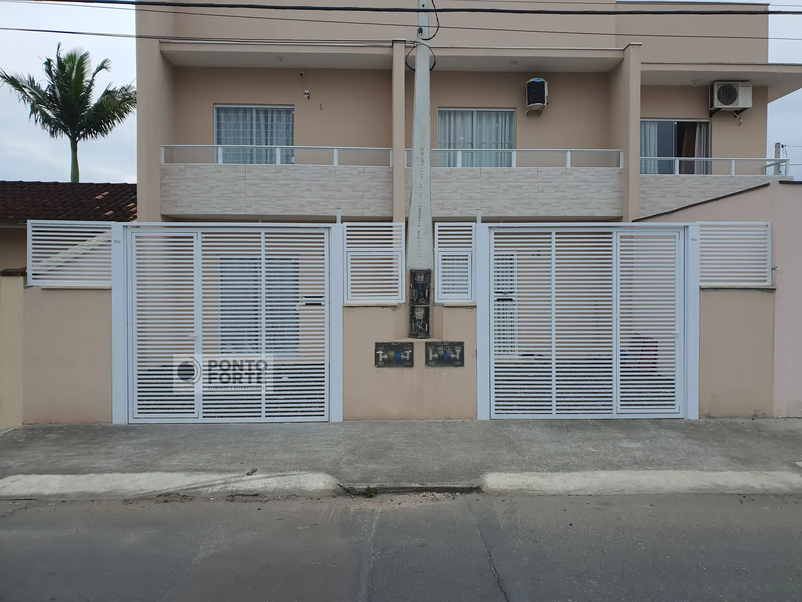 Cerca de alumínio branco vazado com barras verticais, com portão social no mesmo quadro, fabricado e instalado pela Ponto Forte, em Joinville