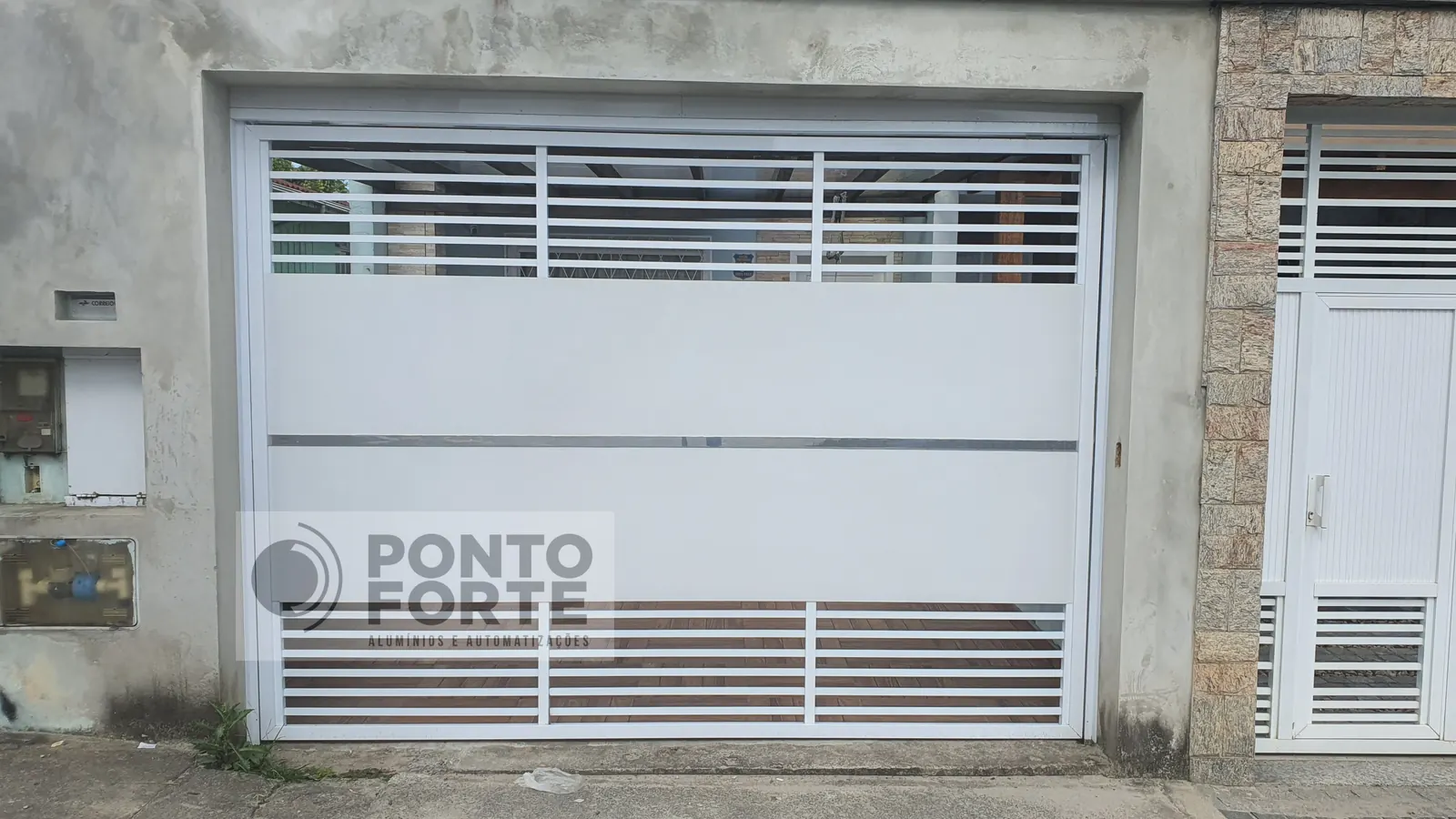Projeto entregue pela Ponto Forte, portão basculante de alumínio branco fechado no centro e vazado em cima e embaixo, em Joinville