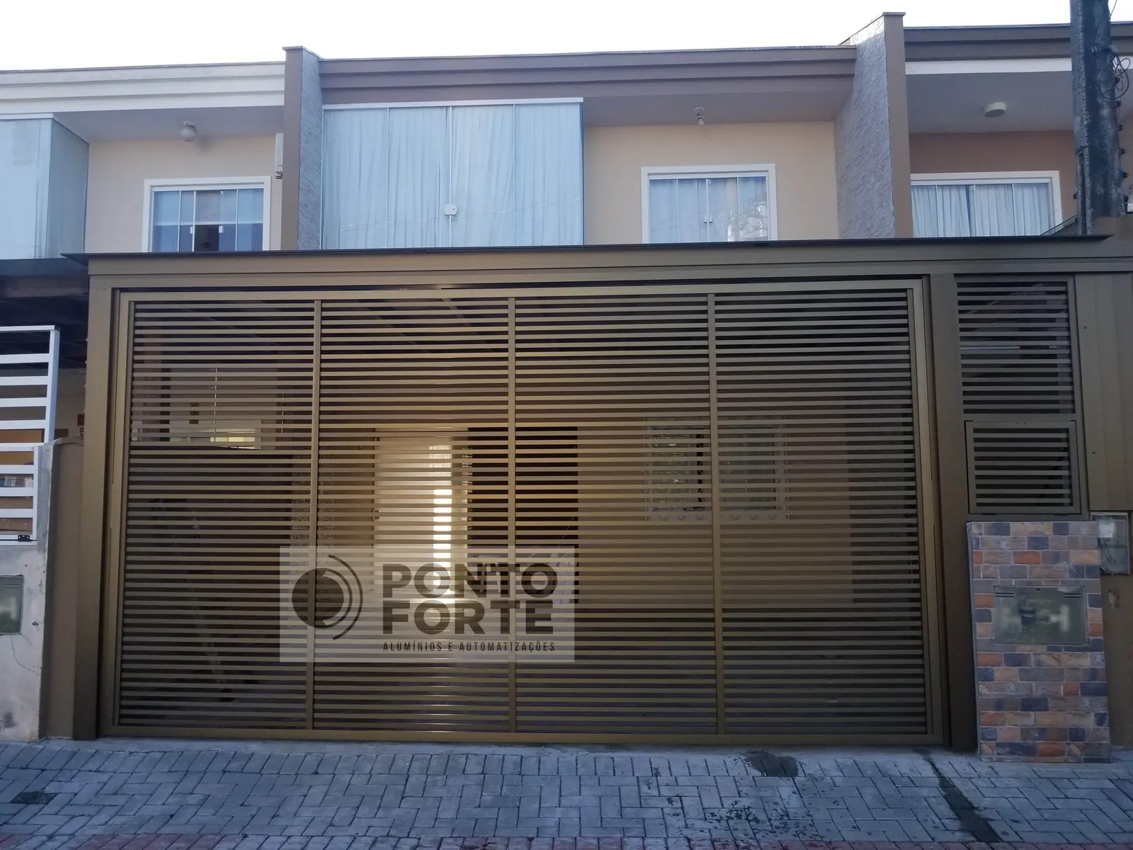 Projeto entregue pela Ponto Forte, portão basculante de alumínio bronze vazado com barras horizontais
