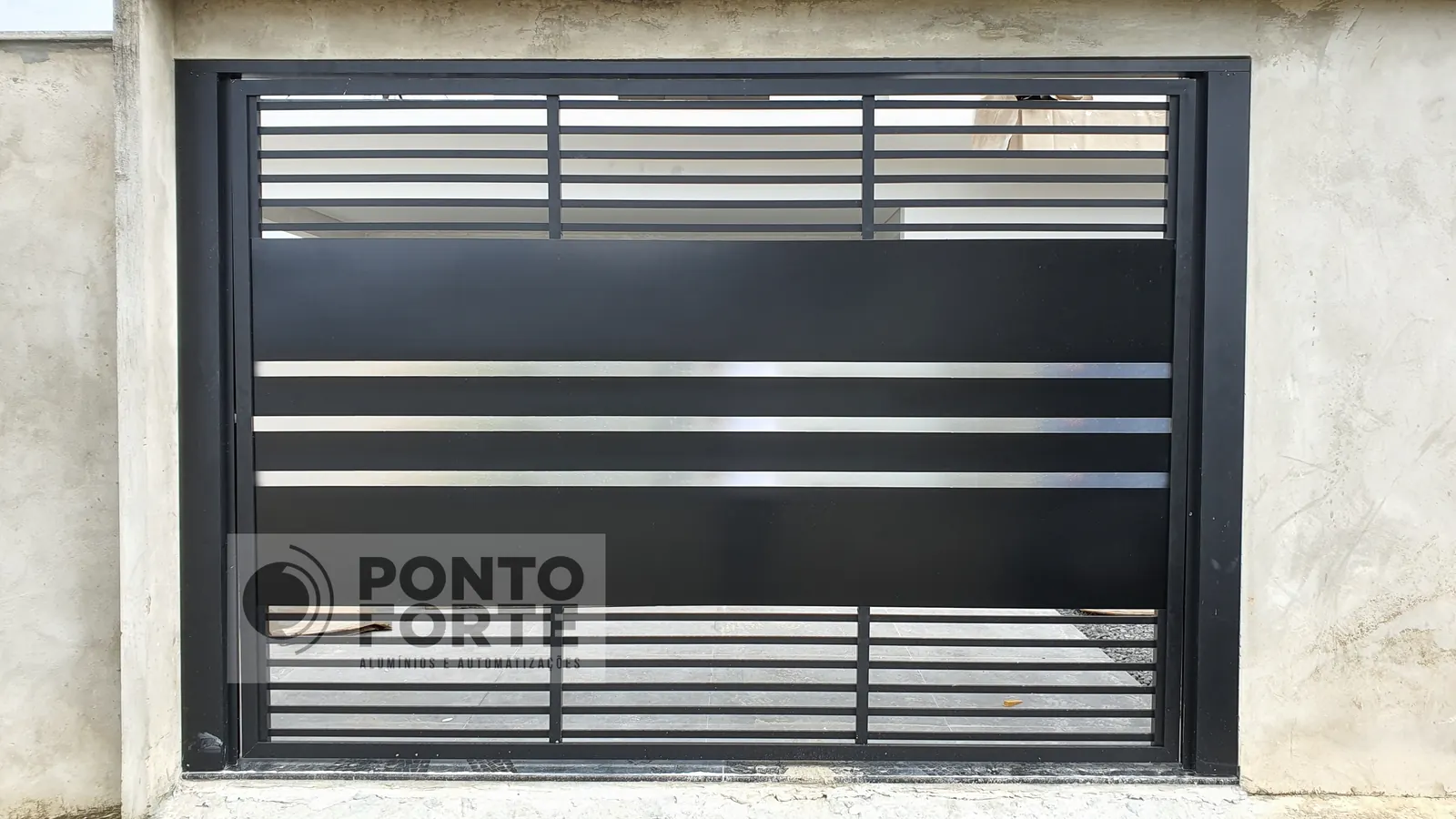 Portão basculante de alumínio preto fechado no centro e vazado em cima e embaixo, fabricado e instalado pela Ponto Forte, em Araquari