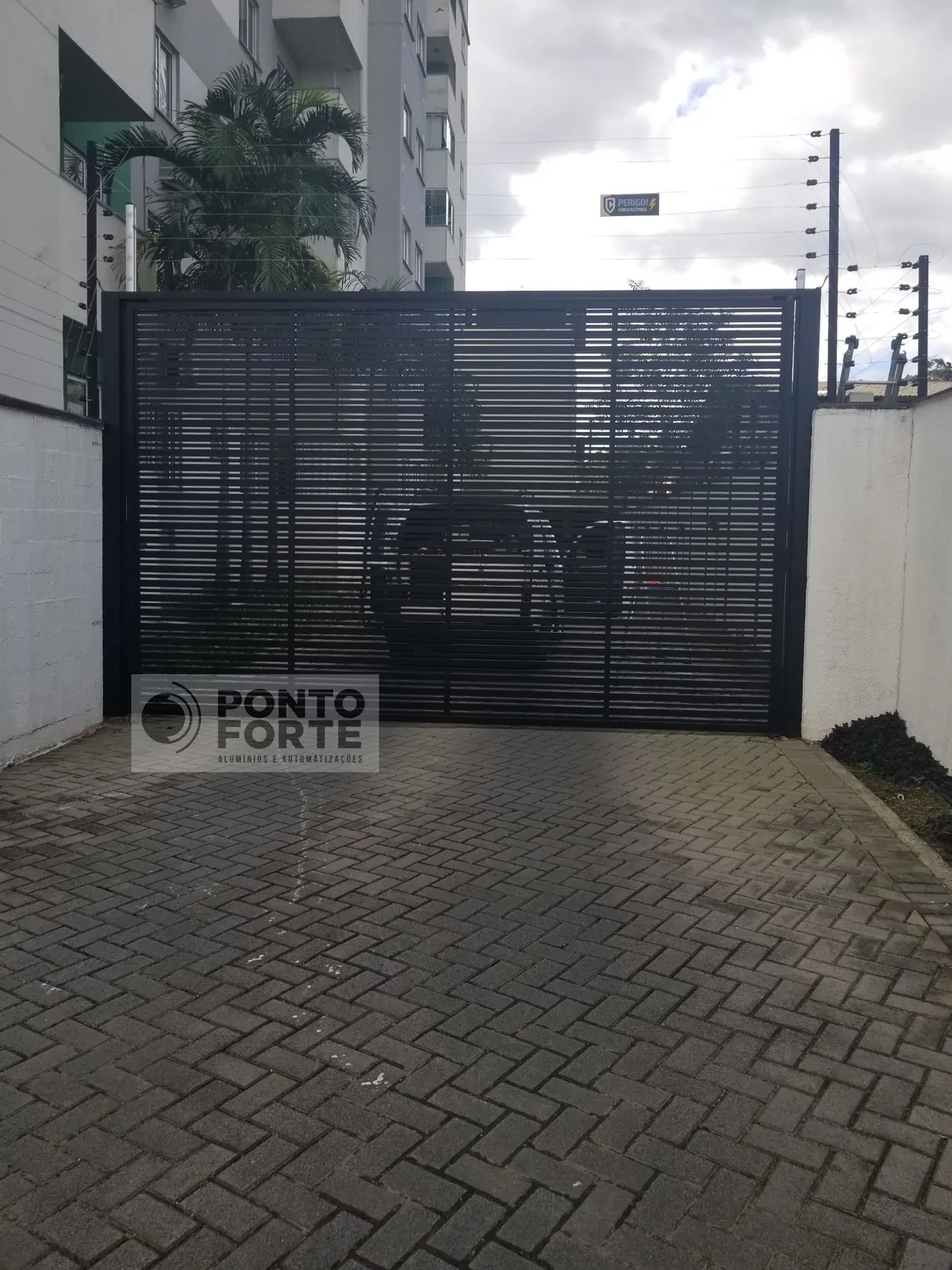 Portão basculante de alumínio preto vazado com barras horizontais, em residência