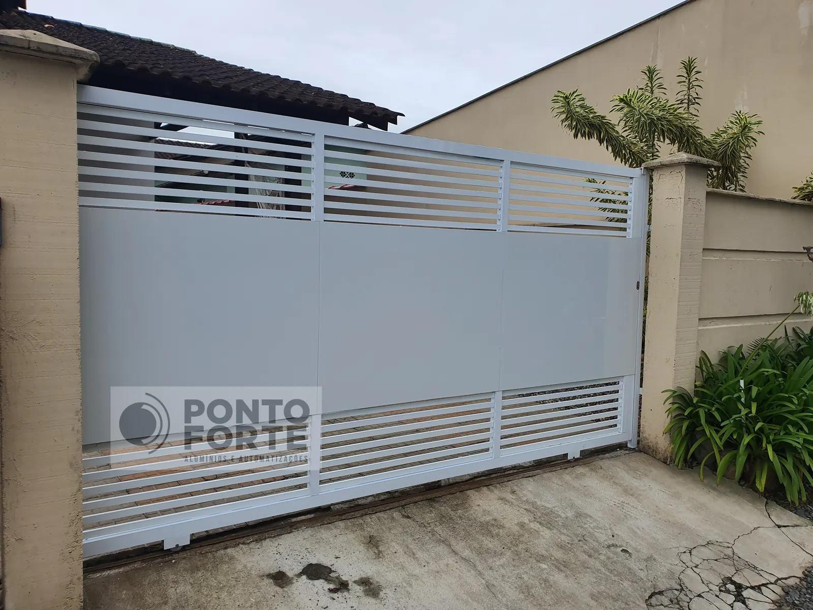 Portão de correr de alumínio branco fechado no centro e vazado em cima e embaixo, fabricado e instalado pela Ponto Forte, em Joinville