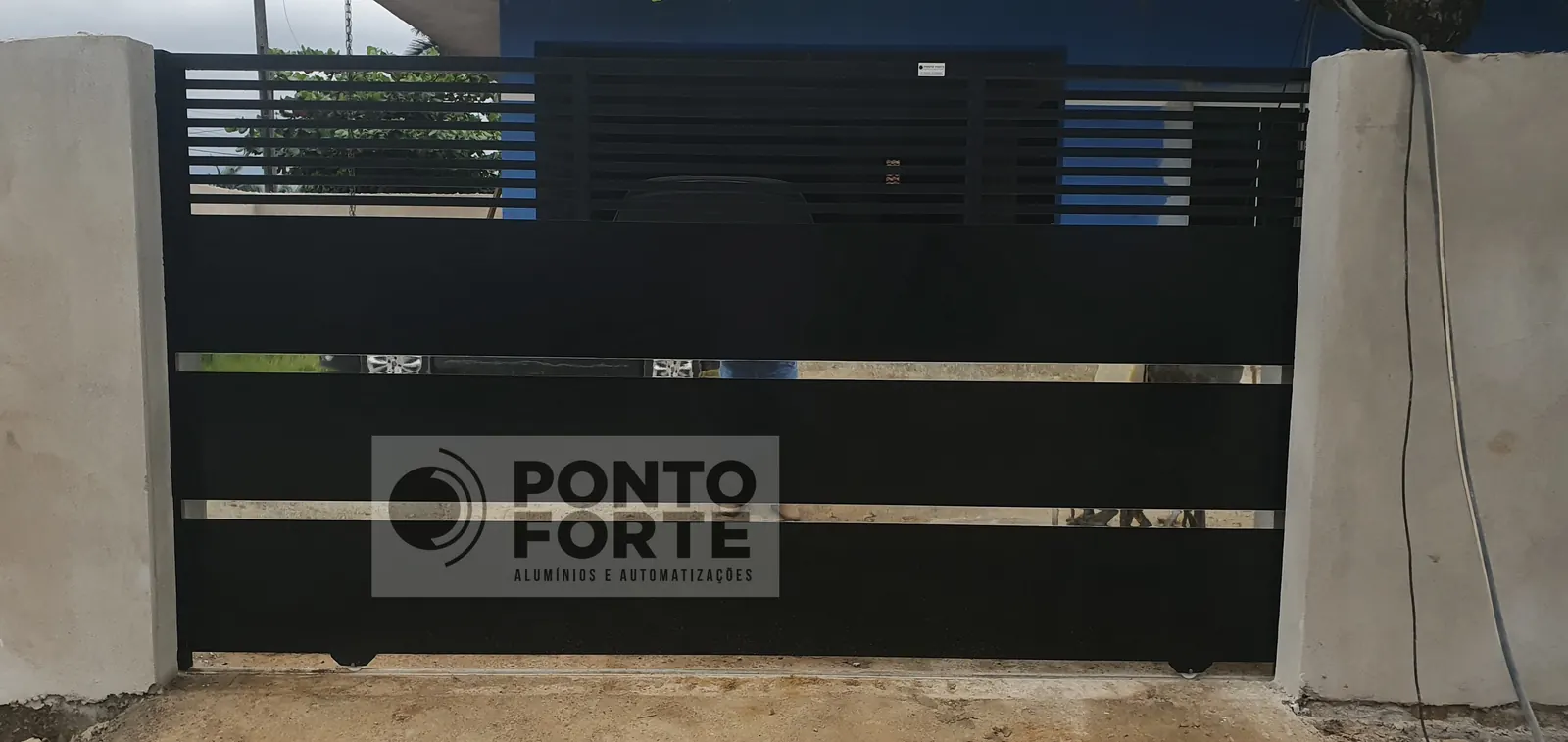 Projeto entregue pela Ponto Forte, portão de correr de alumínio preto fechado no centro e vazado em cima e embaixo