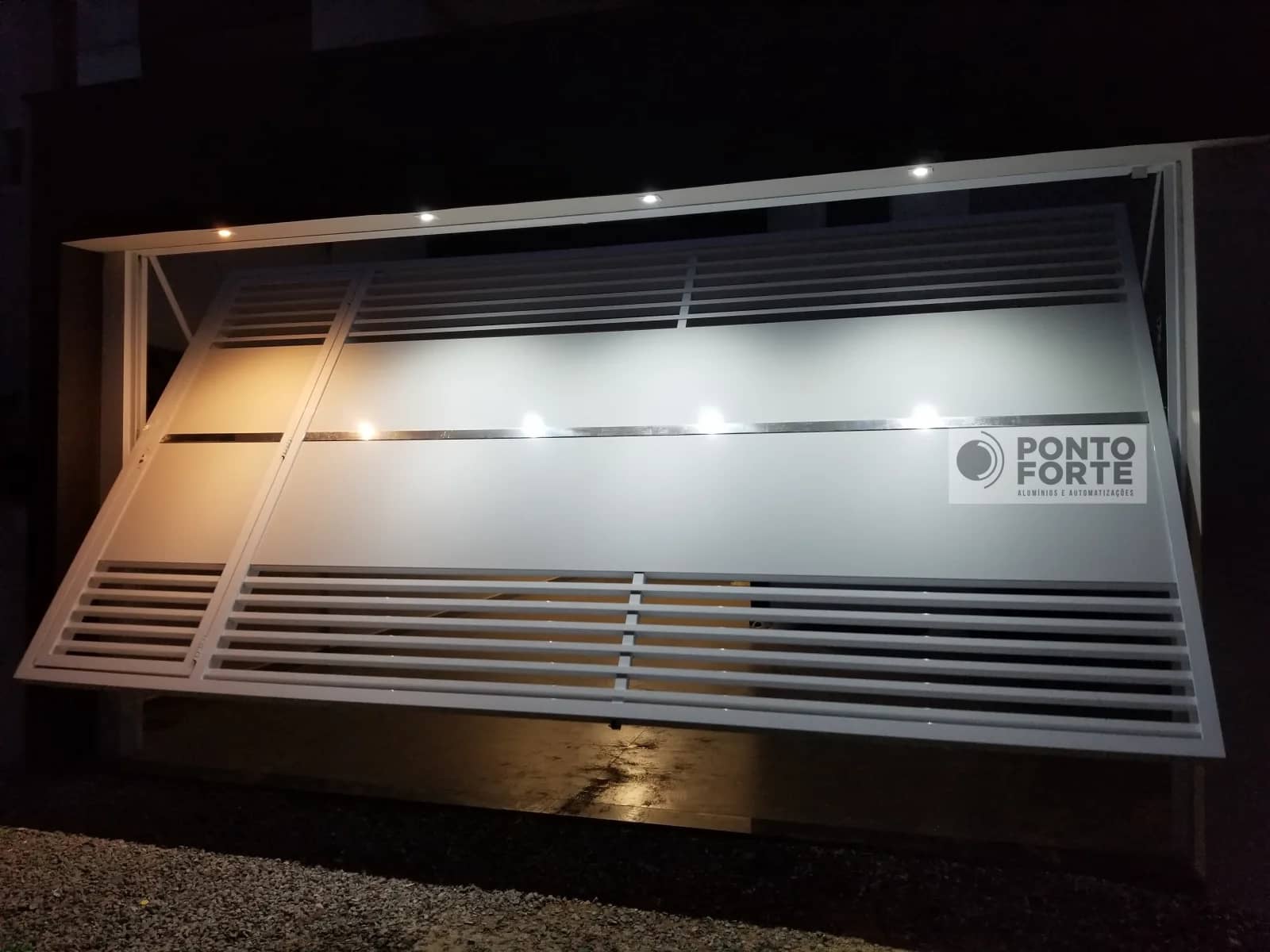 Portão basculante de alumínio prata fechado no centro, com portão social no mesmo quadro, modelo que fabricamos e instalamos em Joinville