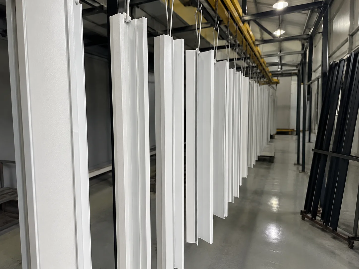 Perfis de alumínio de portão basculante pintados a pó de branco, pendurados na linha de pintura
