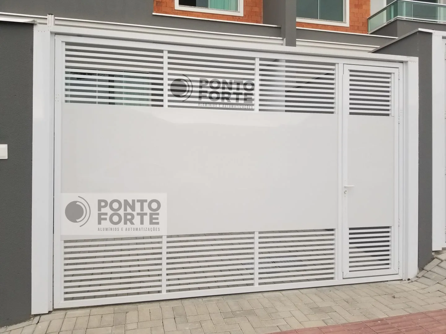 Portão basculante de alumínio branco fechado no centro, com barras vazadas em cima e embaixo e portão social no mesmo quadro, feito pela Ponto Forte em Joinville