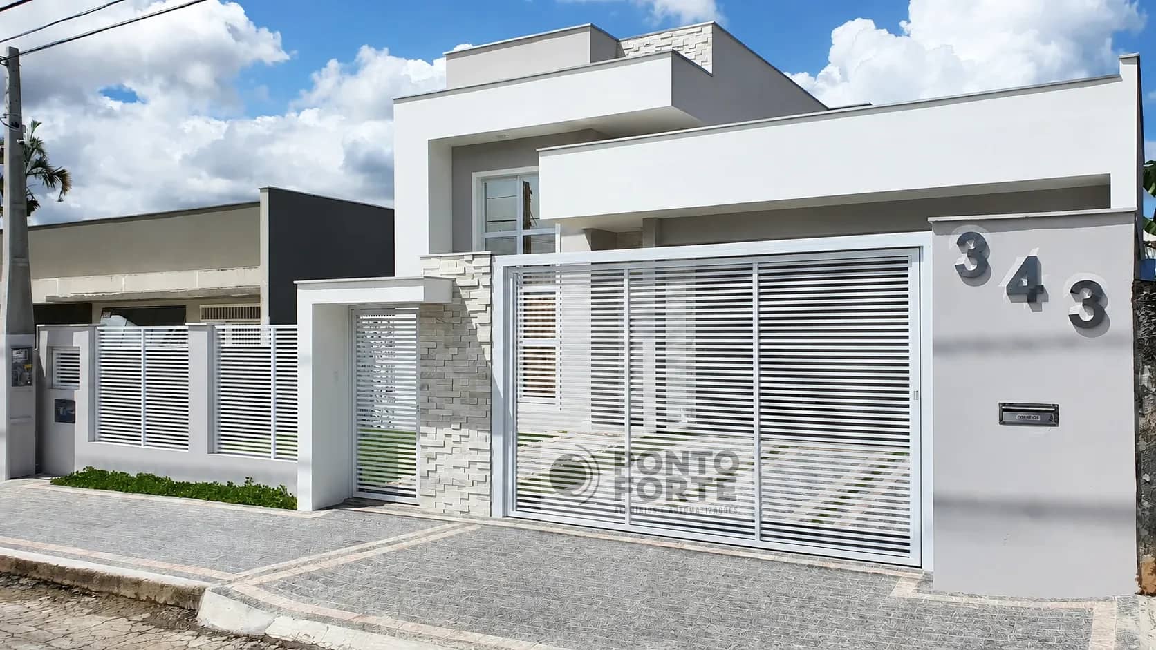 Portão branco vazado com barras feito sob medida, com gradil combinando, em residência de fachada clara em Joinville