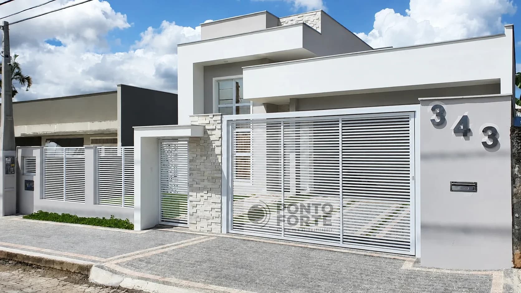 Portão basculante de alumínio branco vazado com barras, com gradil de alumínio combinando, em residência de fachada clara em Joinville