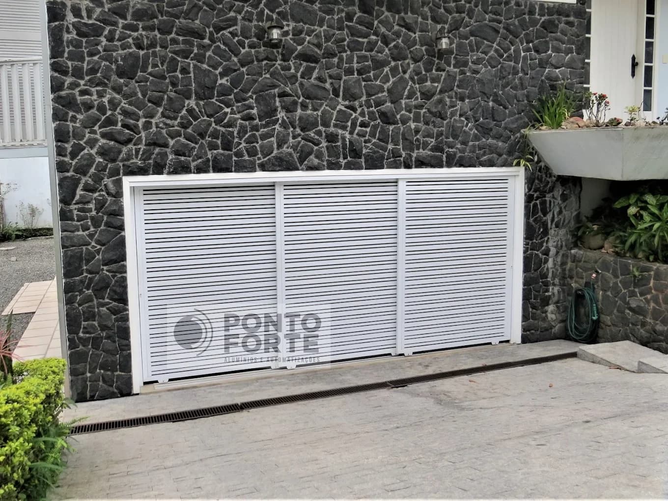 Portão de correr em alumínio branco vazado com barras, instalado em residência em Joinville