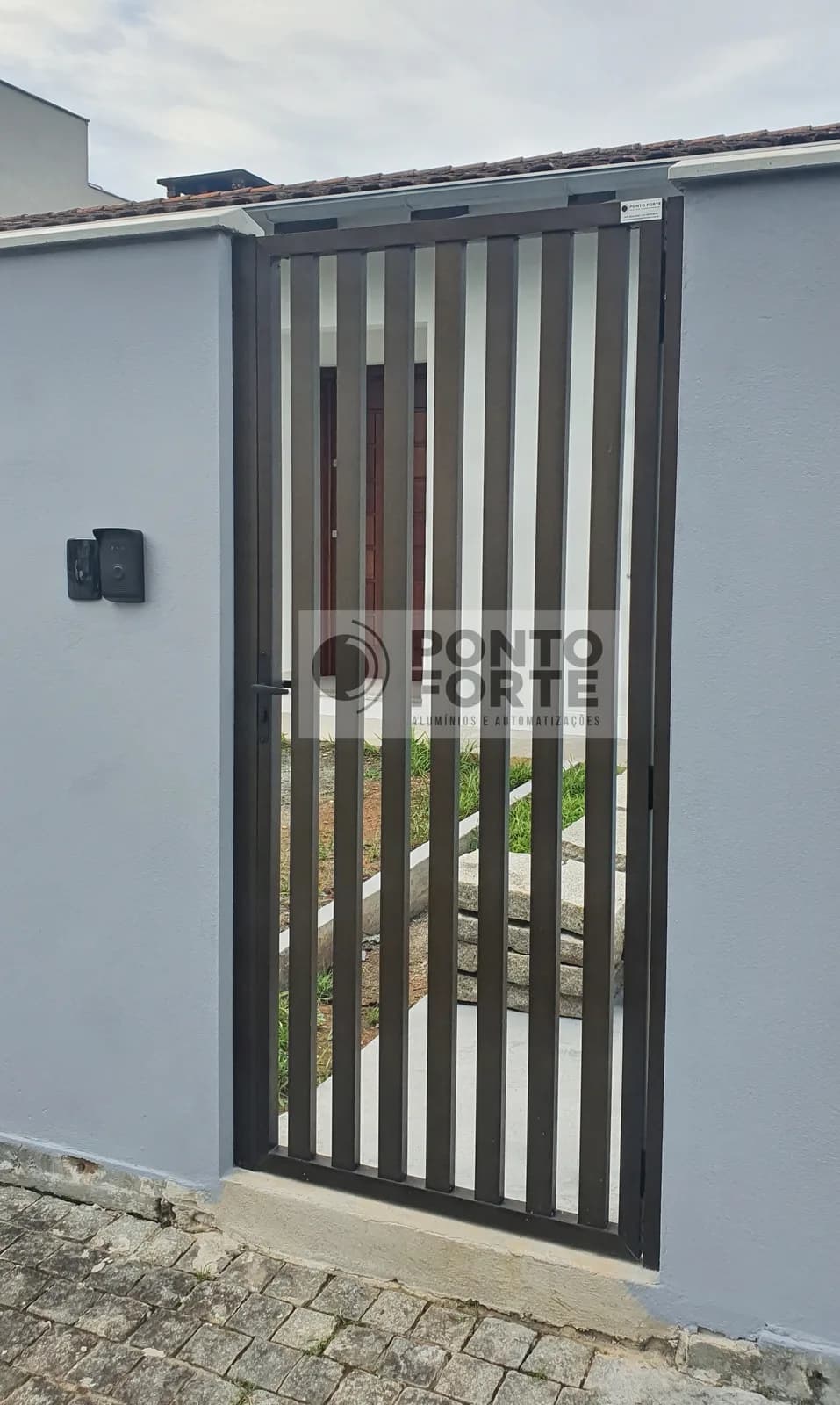 Portão social de alumínio bronze vazado com barras verticais, em muro de residência em Joinville