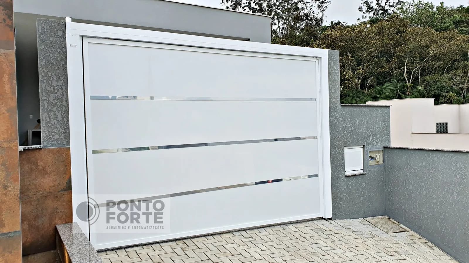 Portão basculante de alumínio branco de chapa lisa com faixas cromadas, instalado em garagem em aclive