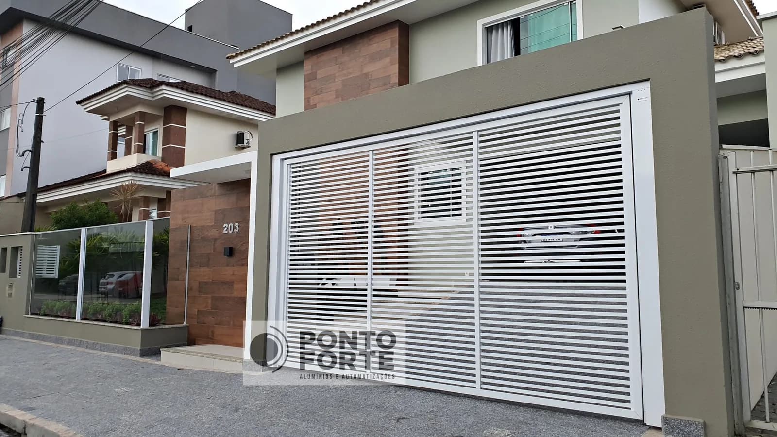 Portão basculante de alumínio branco vazado com barras em garagem dupla de residência em Joinville