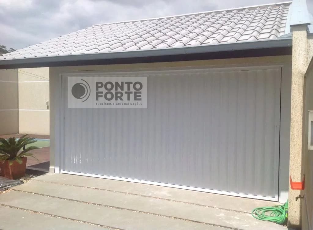 Portão basculante de alumínio branco em lambril frisado vertical, em garagem de residência com telhado colonial