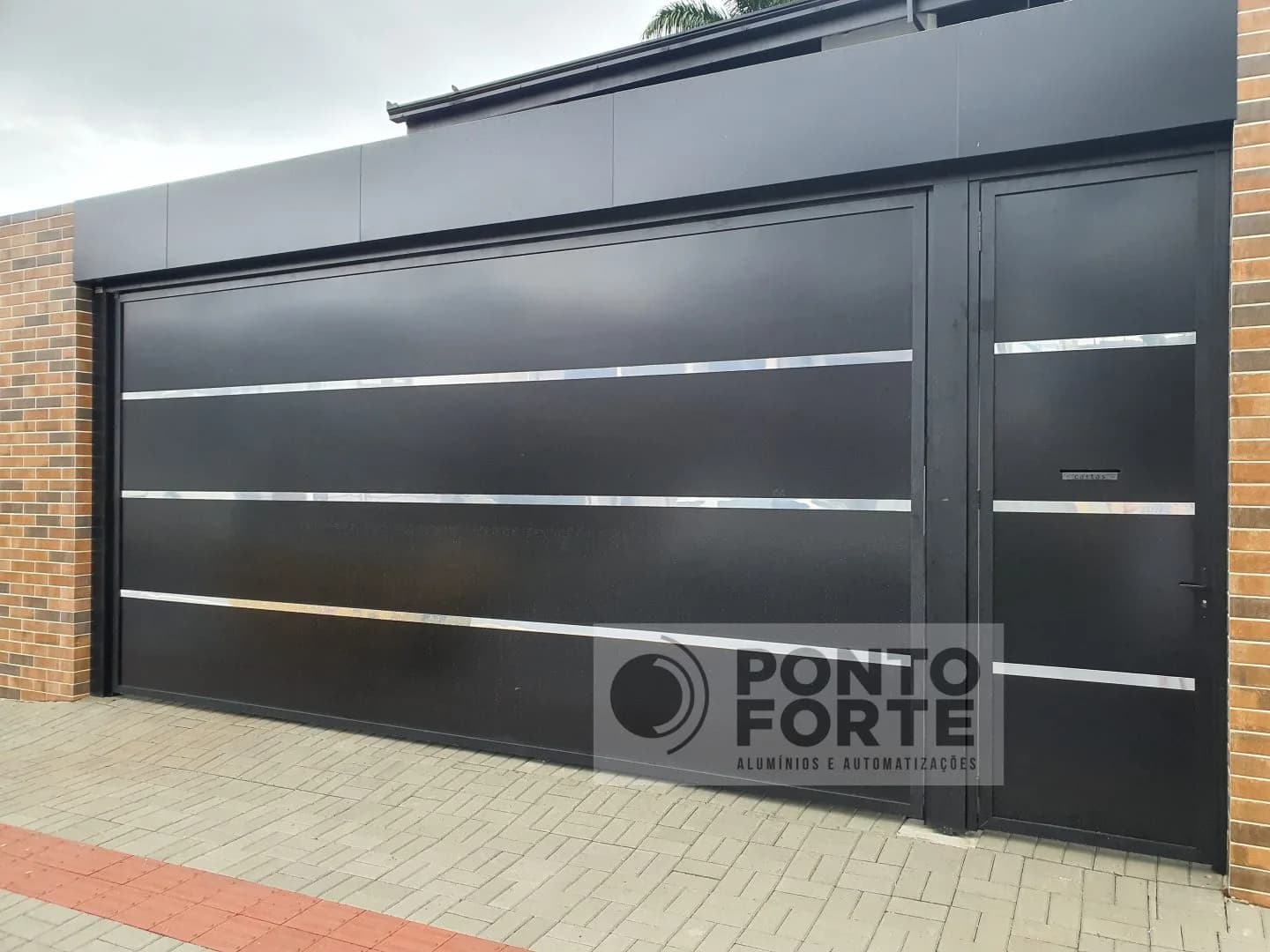 Portão basculante de alumínio preto liso com faixas cromadas em garagem para dois carros, com portão social ao lado