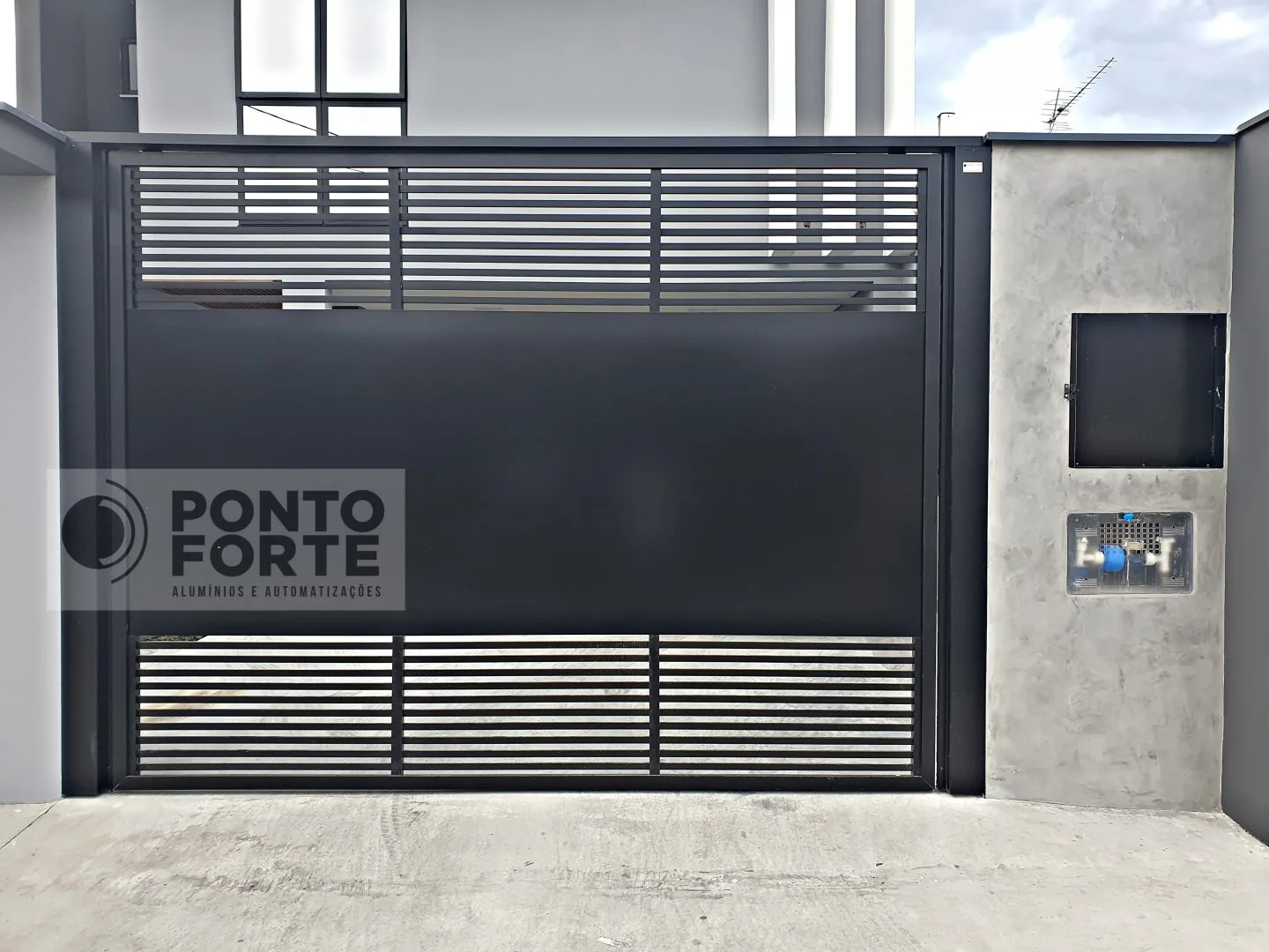 Portão basculante de alumínio preto fechado no centro, com barras vazadas nas faixas superior e inferior