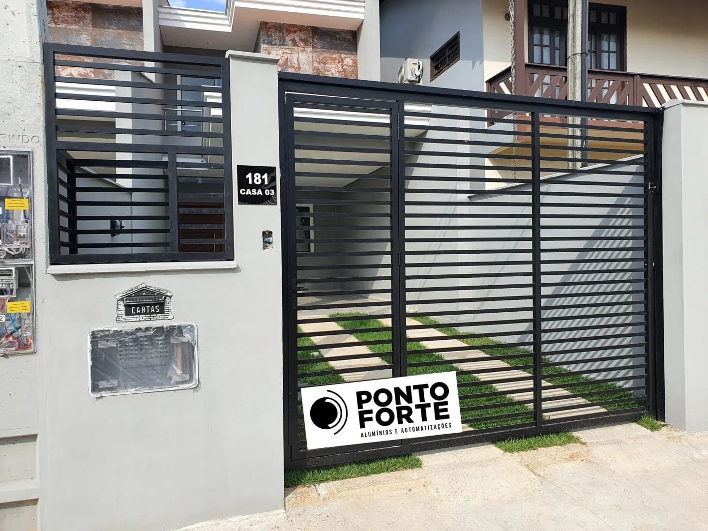 Portão basculante de alumínio preto vazado com barras, com portão social ao lado em vão próprio, no mesmo acabamento, em residência em Joinville