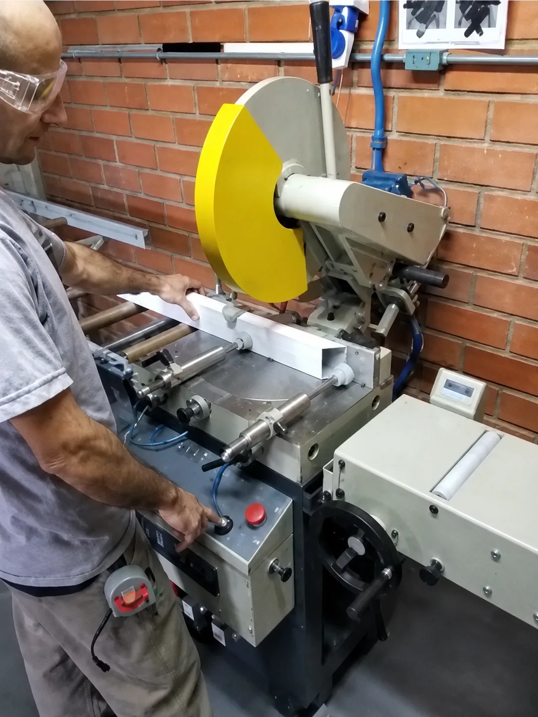 Colaborador da Ponto Forte cortando na serra um perfil de alumínio de portão basculante, na fábrica em Joinville