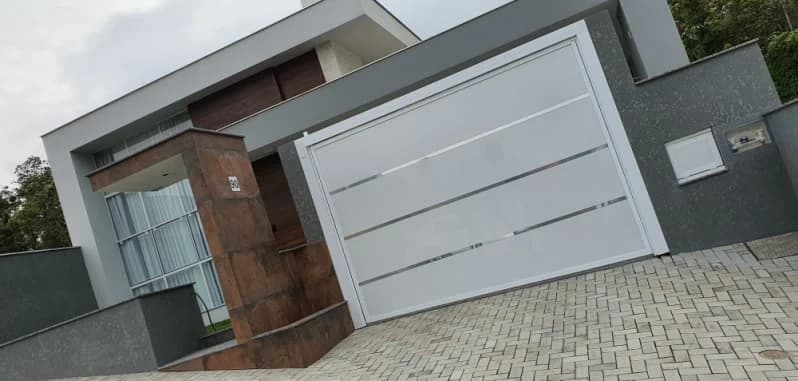 Portão de garagem de alumínio branco com faixas cromadas em casa moderna de rua em declive