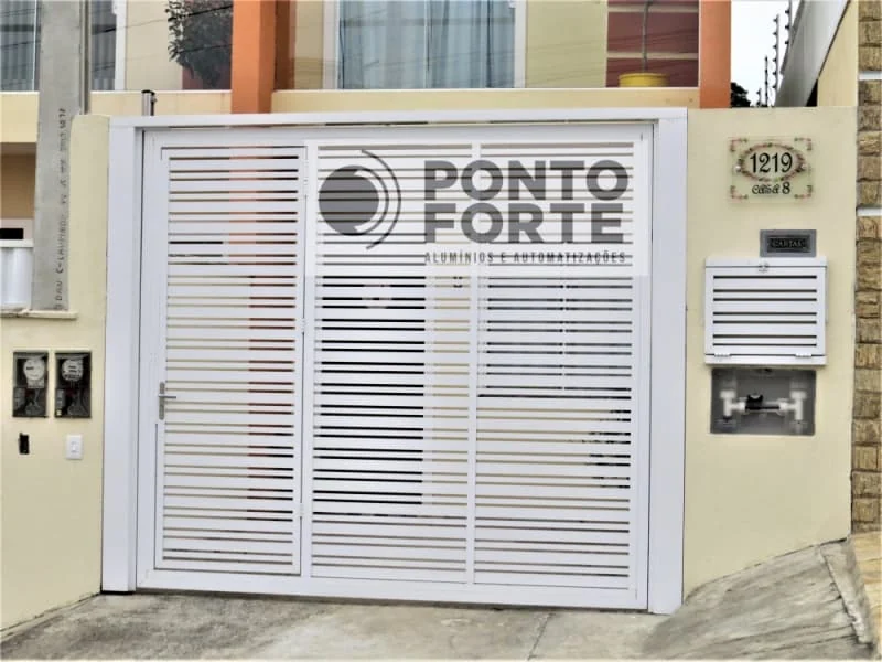 Portão de garagem de alumínio branco vazado com porta social embutida, em frente de casa estreita