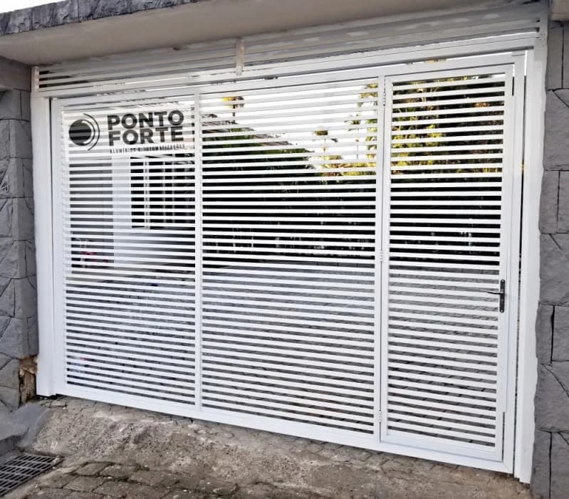 Portão de garagem de alumínio branco vazado com porta social embutida, com a maçaneta da porta de pedestre à direita