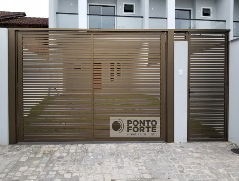 Portão de garagem de alumínio bronze vazado com barras e porta social separada ao lado, no mesmo desenho