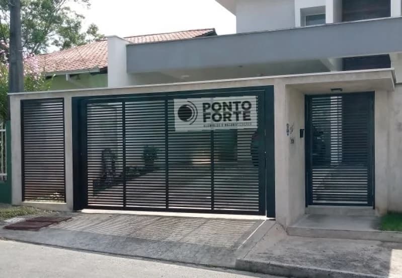 Portão de garagem de alumínio preto vazado com porta social separada no mesmo muro e no mesmo desenho