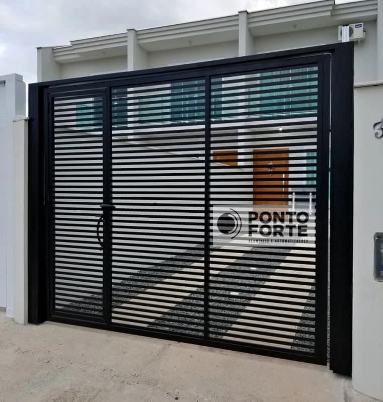 Portão de alumínio preto vazado com barras horizontais e maçaneta no centro, em frente de casa