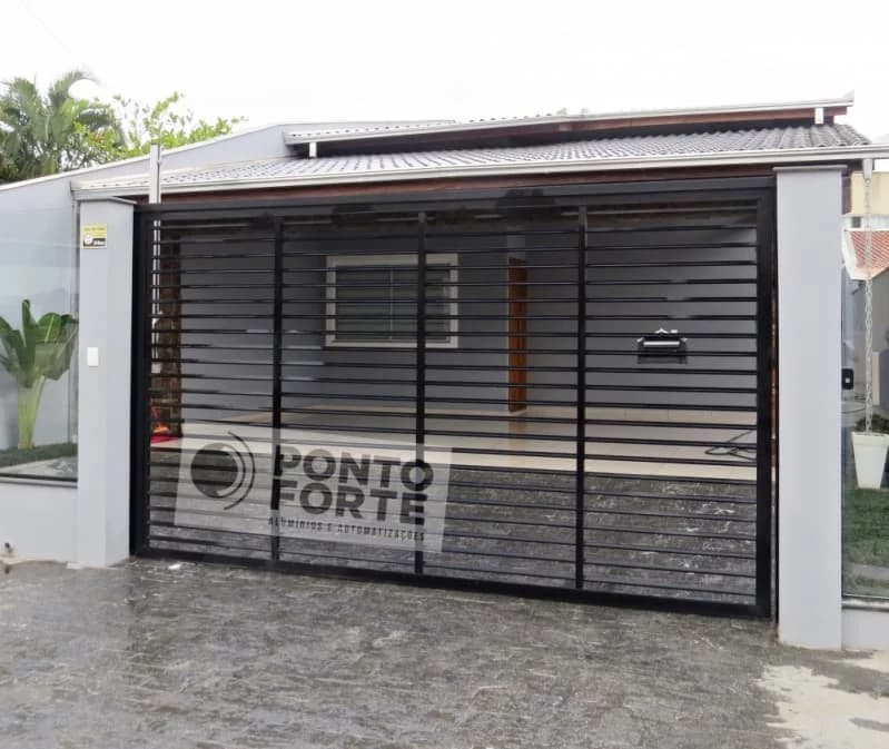 Portão de garagem de alumínio preto vazado com barras horizontais em frente de casa com piso molhado